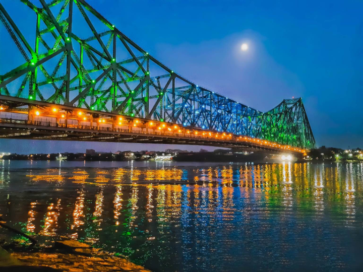 Howrah Bridge illuminated at night over the Hooghly River in Kolkata.