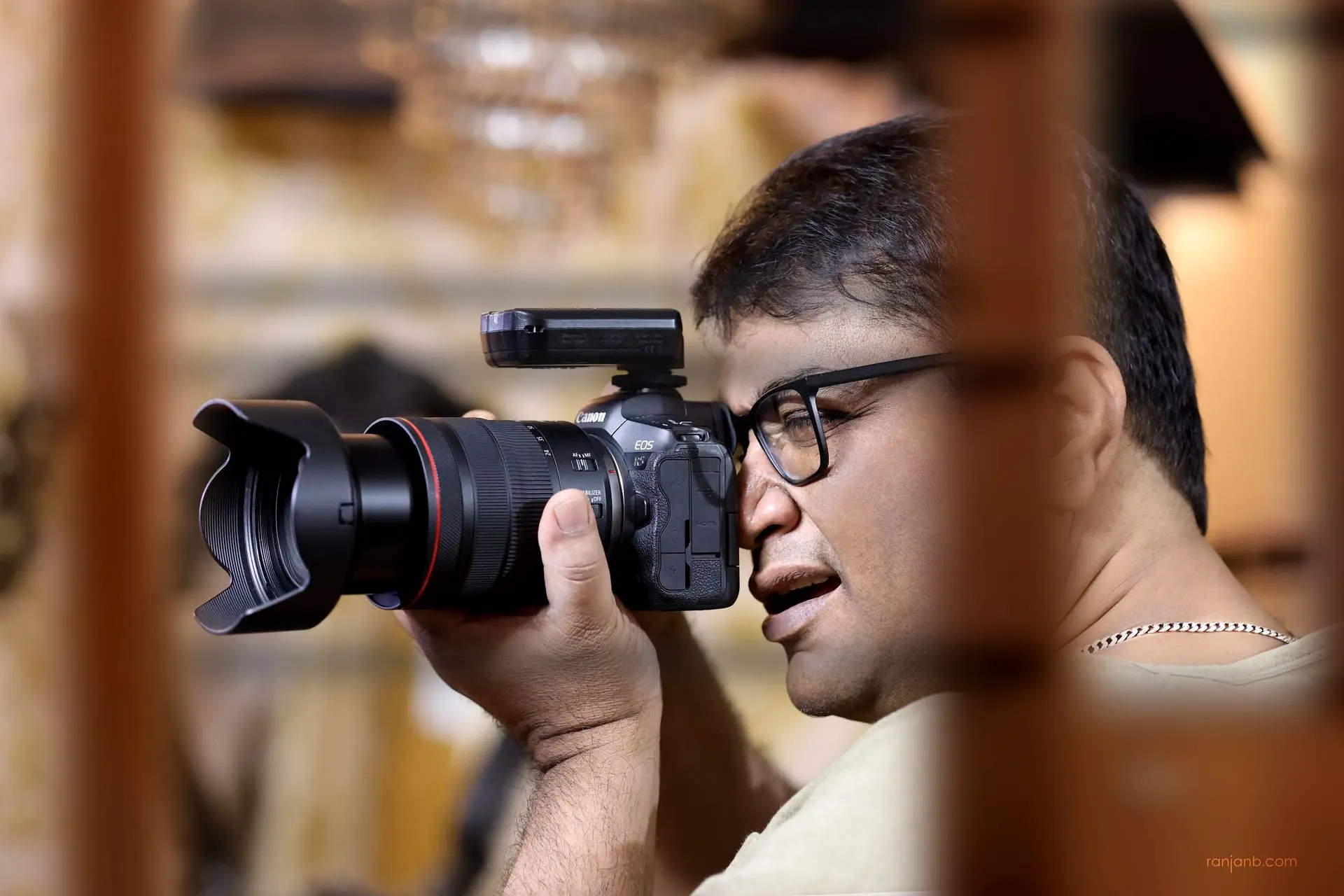 Ranjan Bhattacharya holding a camera at eye level, ready to shoot — photographer, author, and storyteller.
