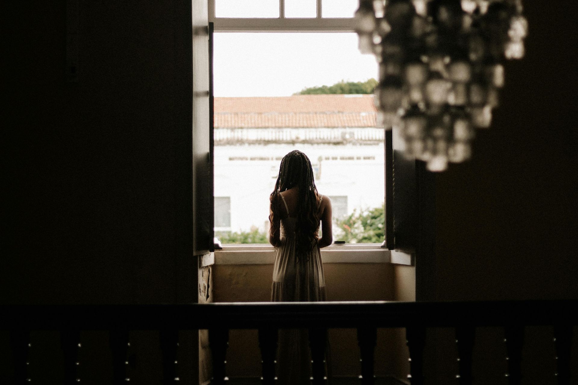 A professional woman standing by a window, reflecting on intentional visibility and authenticity in personal branding in 2026.