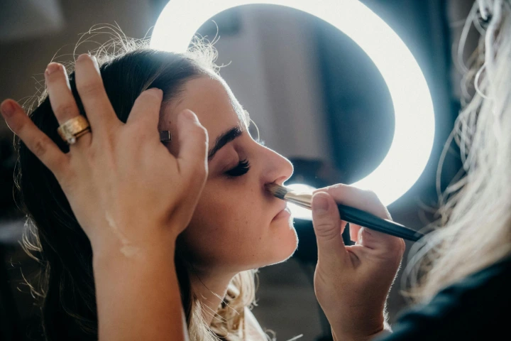 Improper makeup planning and lighting are common mistakes that affect undergarment advertising shoots Makeup artist applying makeup to a model under ring light during a professional studio photoshoot