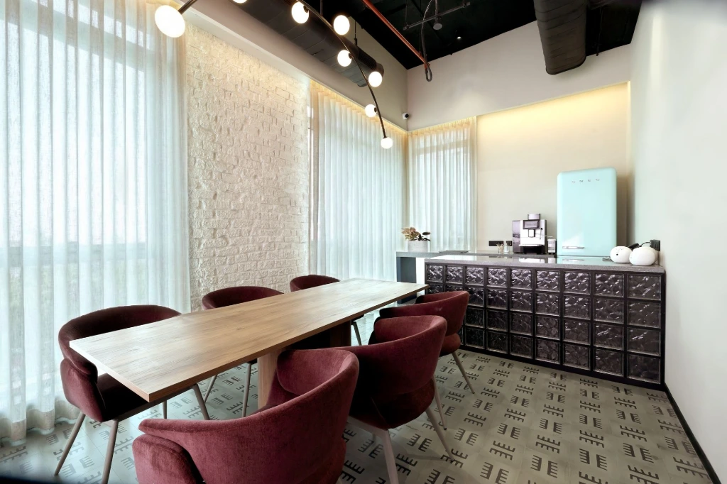 A thoughtfully designed office cafeteria that balances functionality, warmth, and everyday employee interaction Corporate office cafeteria with shared dining table, soft lighting, and a warm yet functional interior design