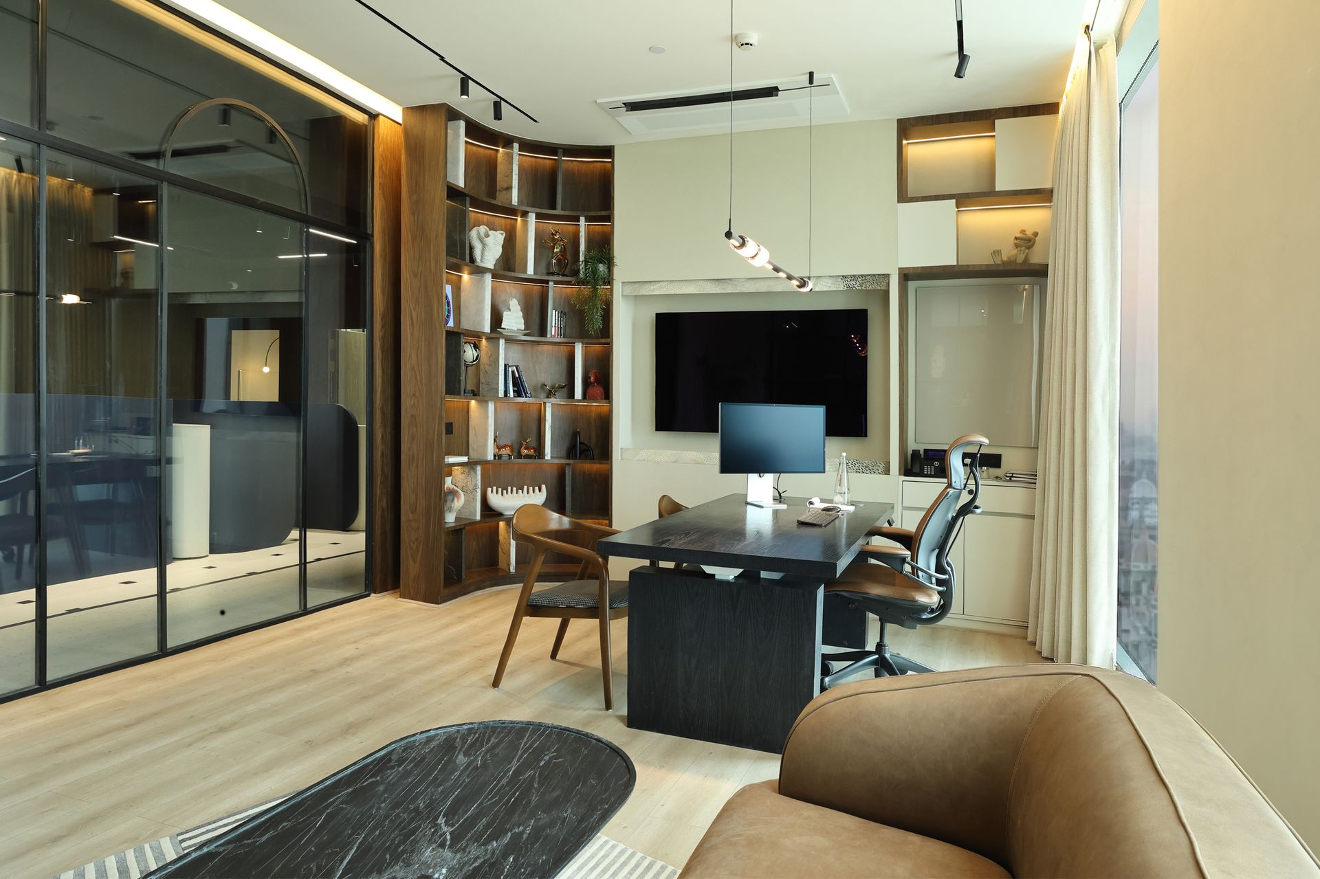 Executive office interior at Khemka House in Kolkata, designed by Green Square Delhi, featuring modern desk setup, wood shelving and glass meeting room partition.