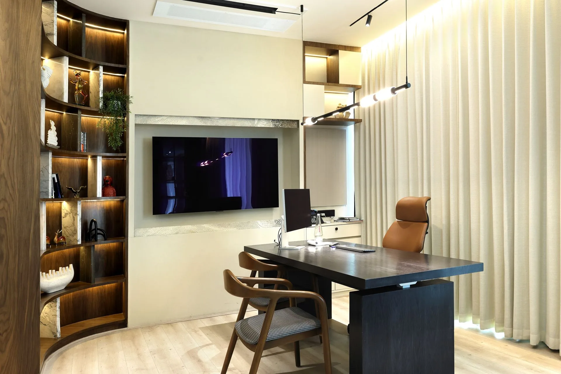 Executive office interior at Khemka House Kolkata designed by Green Square Delhi, featuring modern desk, wooden shelving with display lighting and full height curtains.