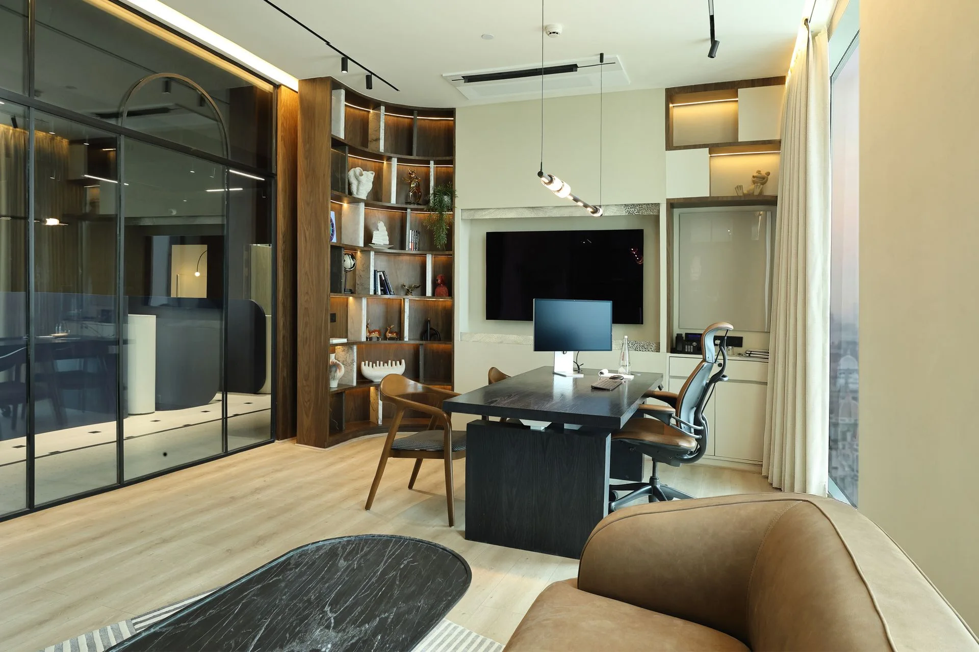 Executive office interior at Khemka House in Kolkata, designed by Green Square Delhi, featuring modern desk setup, wood shelving and glass meeting room partition.