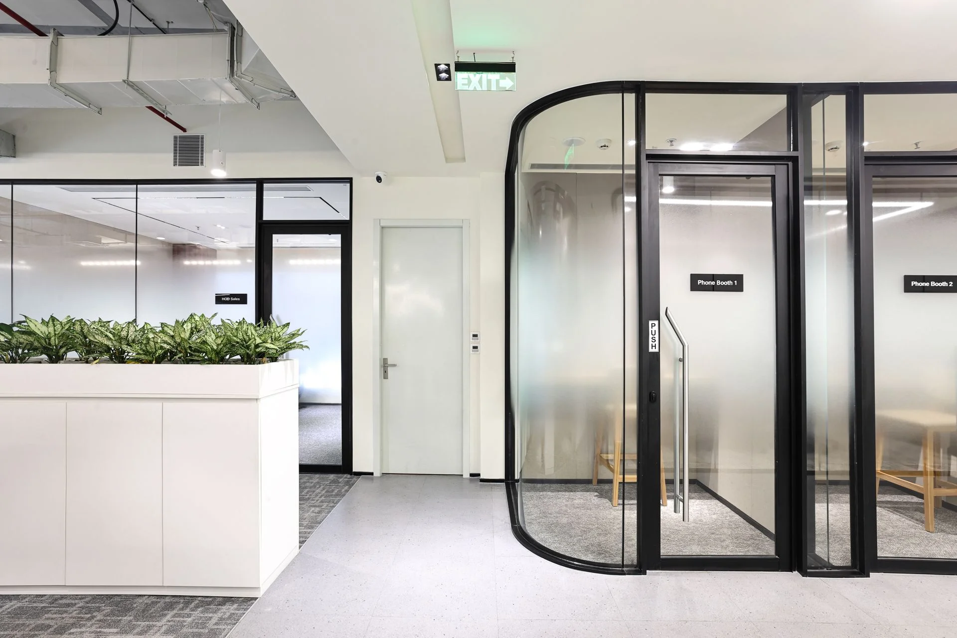 Commercial interior photography featuring modern glass phone booths, acoustic meeting pods, indoor planters and contemporary corporate office architecture.