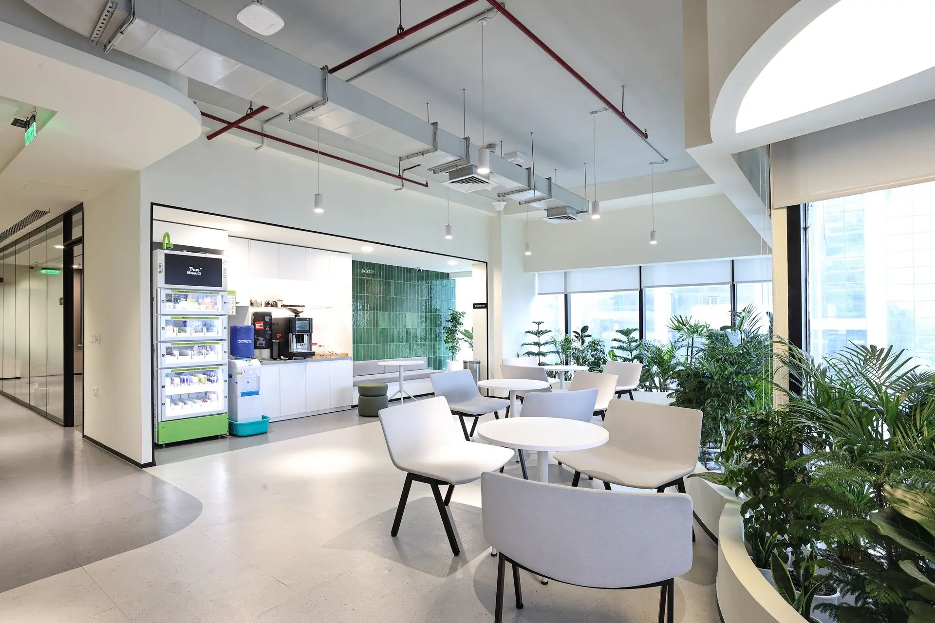 Commercial office breakout space interior photography featuring a modern corporate cafeteria, coffee station, lounge seating, indoor plants and contemporary workplace design.