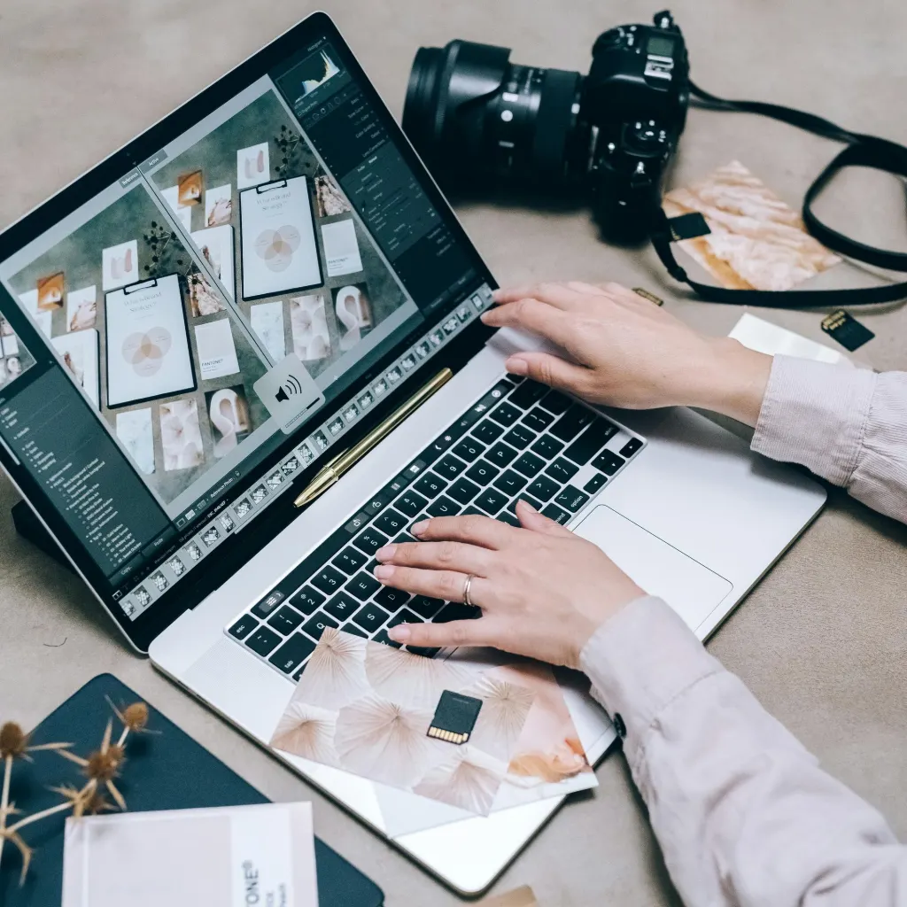 Indian photographer viewing portfolio website on laptop with camera gear on desk