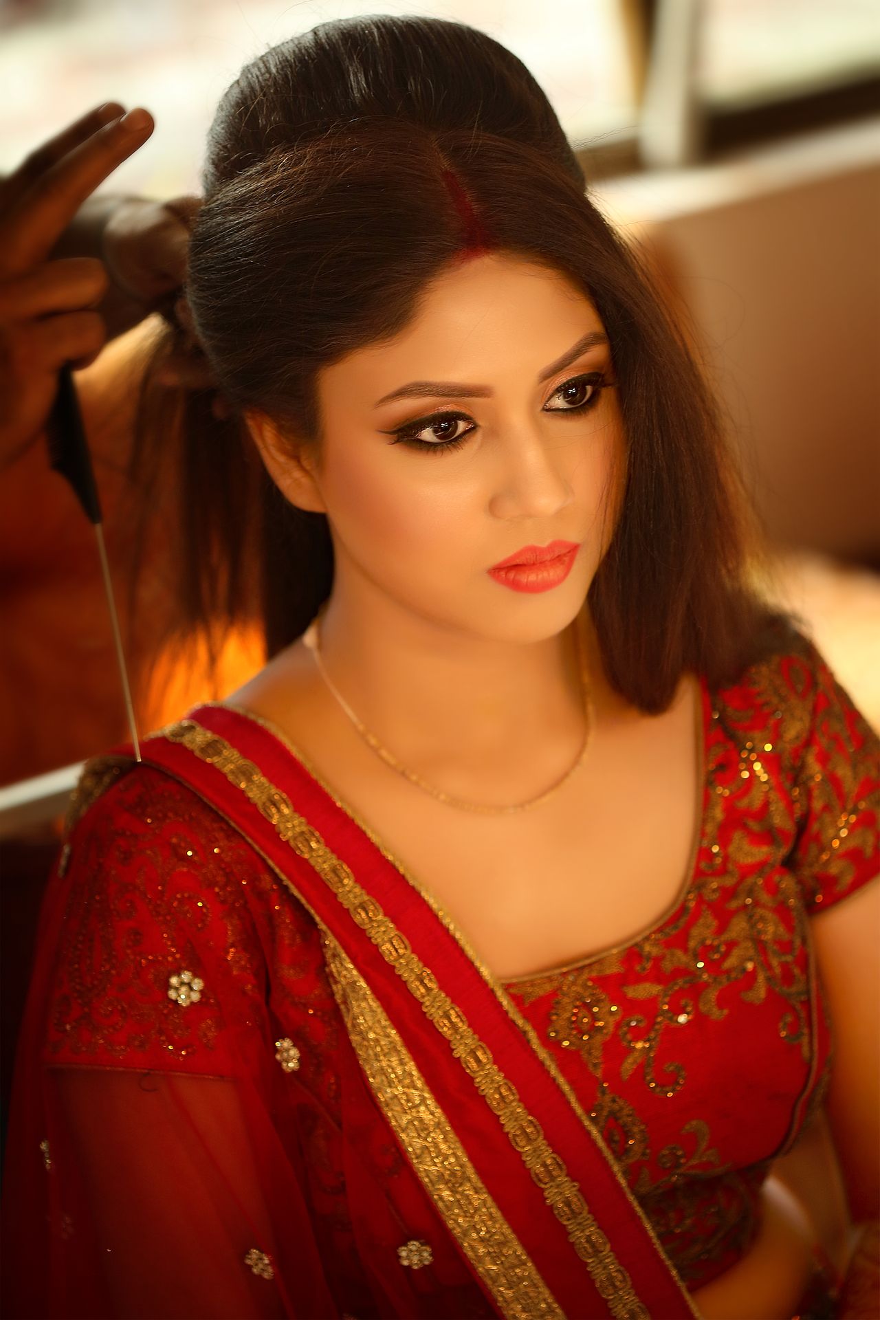 A candid moment from Debarati Sarkar's wedding, while doing her bridal makeup, photographed by the best wedding photographer in Kolkata - Ranjan Bhattacharya