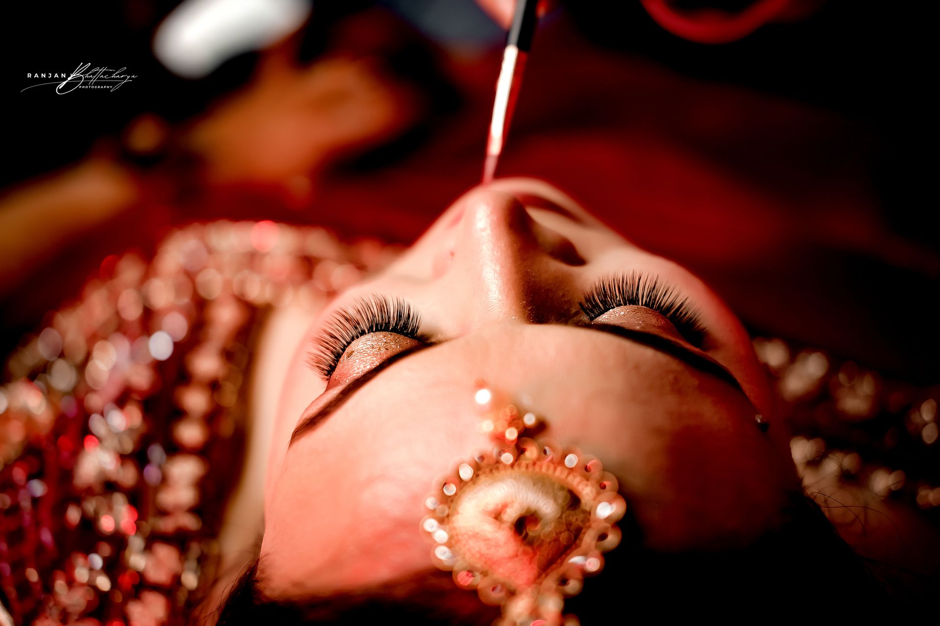 A candid moment from Ruhi Singh's wedding, while doing her bridal makeup, photographed by the best wedding photographer in Kolkata - Ranjan Bhattacharya