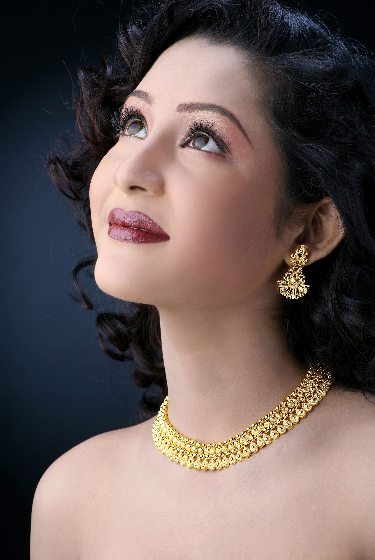 A beautifully crafted traditional gold necklace photographed against a gray background by best jewelry photographer Ranjan Bhattacharya in Kolkata.